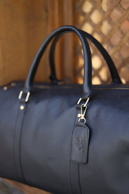 Close-up of a dark blue leather bag with a visible brand logo on a blurred background